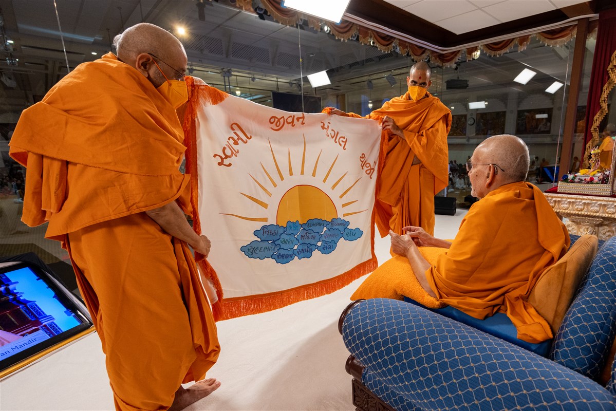 Aksharviharidas Swami and Paramtattvadas Swami present a decorative shawl to Swamishri 