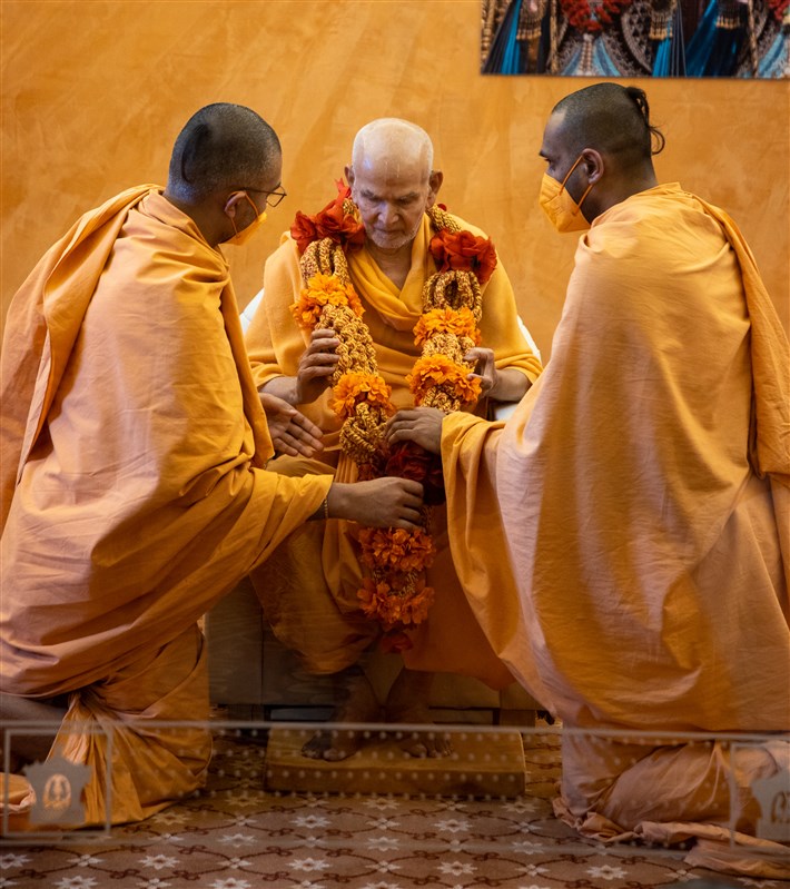 Paramsetudas Swami and Amalkirtidas Swami honour Swamishri with a decorative garland