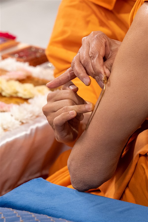 Swamishri applies a tilak on his arm