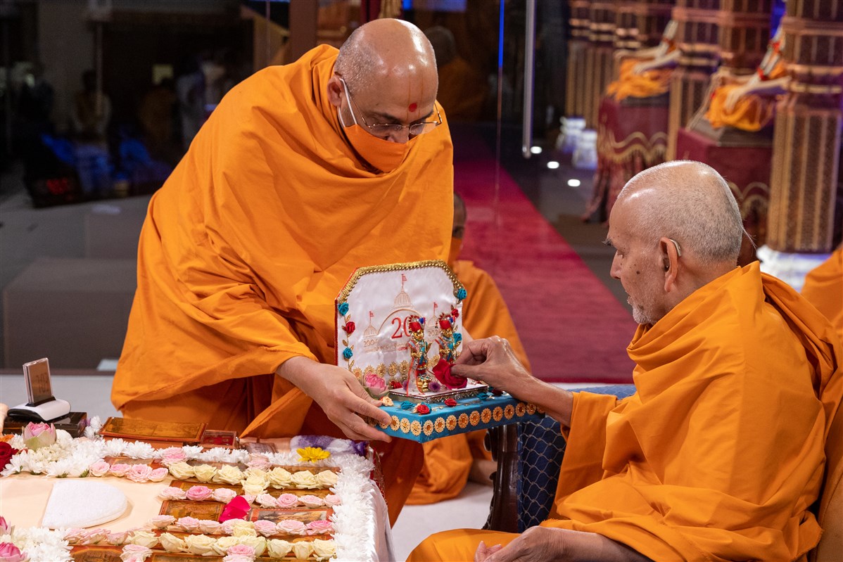 Swamishri offers a rose flower to Shri Harikrishna Maharaj and Shri Gunatitanand Swami Maharaj