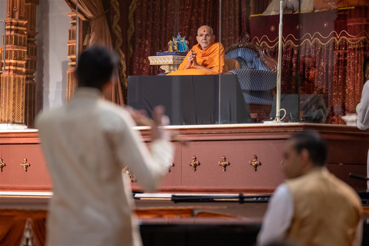 Swamishri greets the devotees with folded hands as the musicians offer their talent in devotion