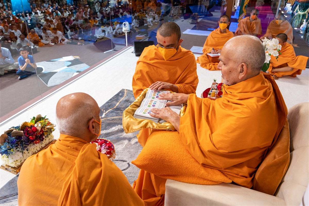 Swamishri blesses a gift that will be given to each family reminding them of 'Daily Satsang Time'