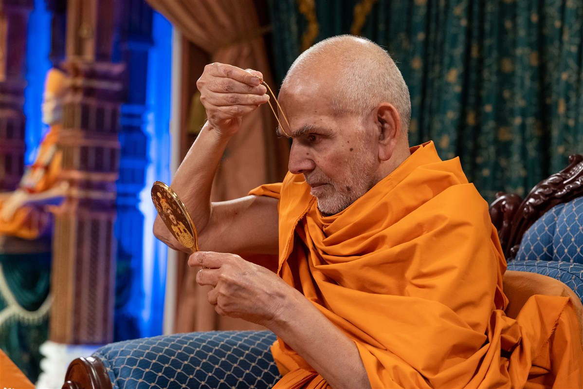 Swamishri commences his puja by applying a tilak on his forehead