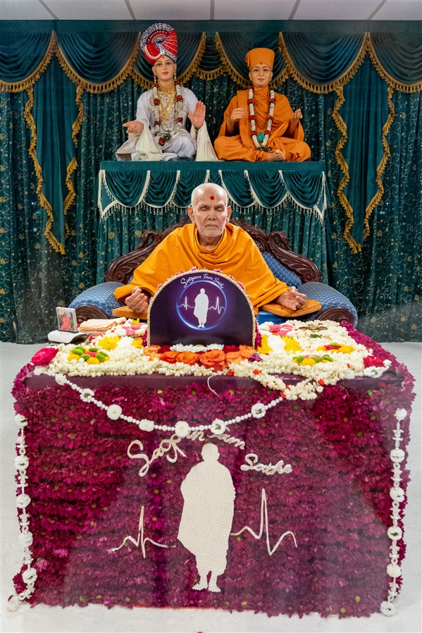 Swamishri meditating in his puja, which was adorned with fresh flowers, depicting the theme of the <a href="https://www.baps.org/News/2023/Sagpan-Tam-Sathe--Mahila-Din-23540.aspx" target="blank" style="text-decoration:underline; color:blue;" >Mahila Din</a> 'Sagpan Tam Sathe: A Spiritual Bond that Defies Boundaries'