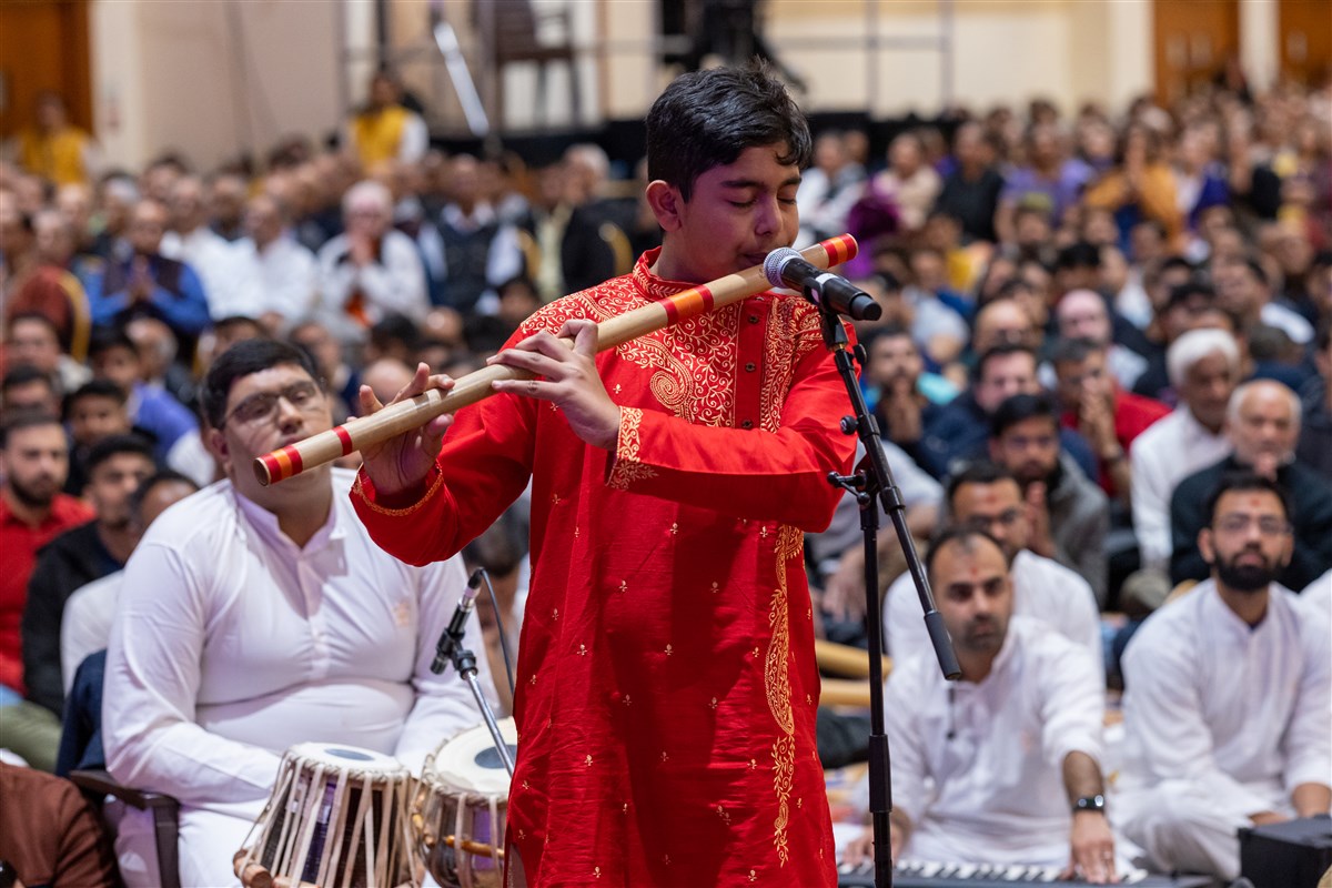 12-year-old child prodigy, Mayukhjit Chakraborty, plays the Indian flute while Swamishri greets the devotees