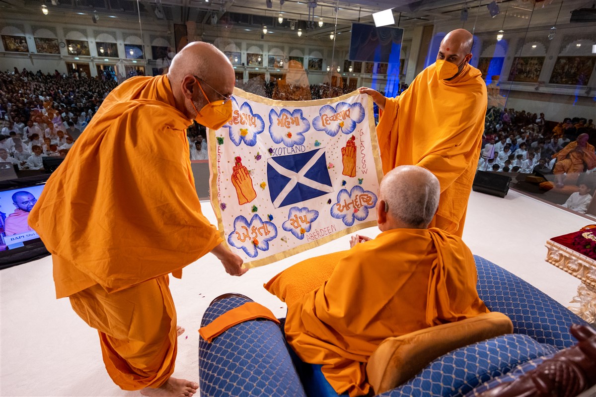 Tyagprakashdas Swami and Akhandyogidas Swami present a decorative shawl to Swamishri