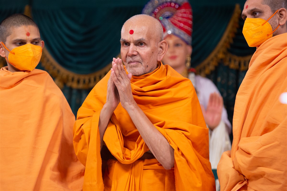 Swamishri greets the devotees with folded hands as he departs from the morning assembly