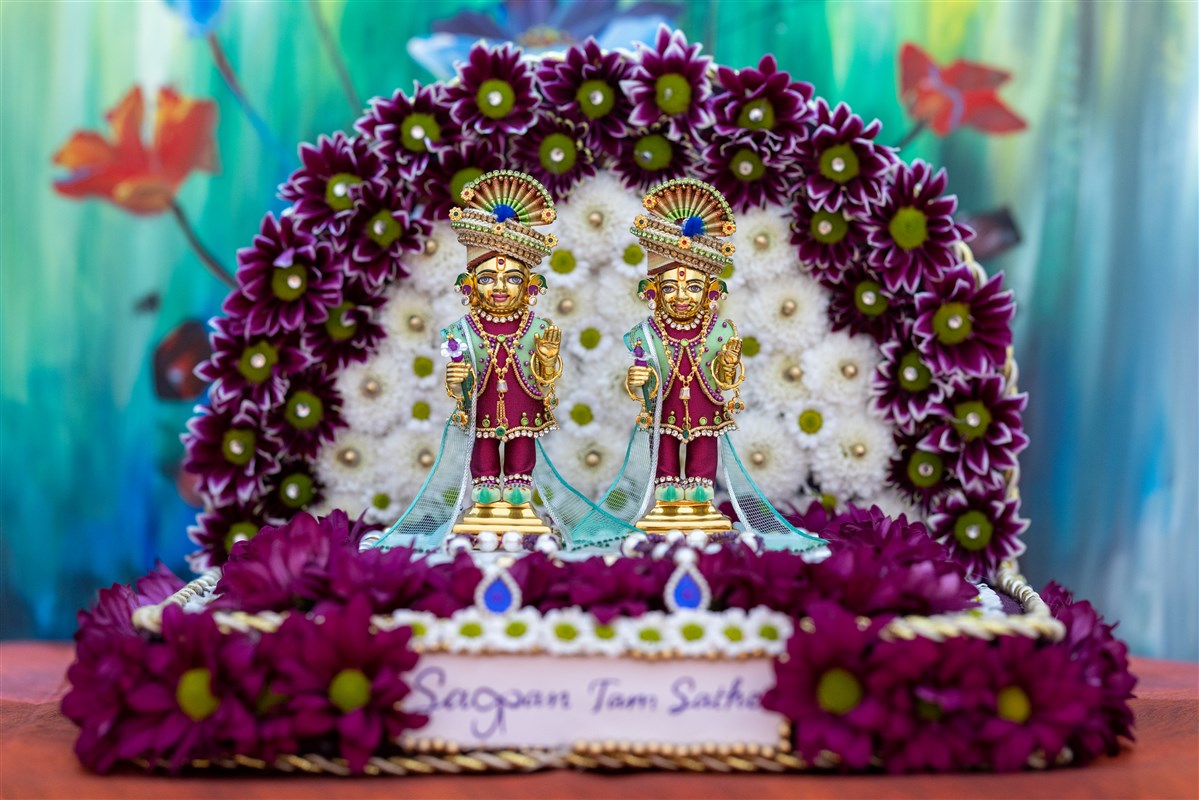Shri Harikrishna Maharaj and Shri Gunatitanand Swami Maharaj presiding in a decorative sinhasan hand-crafted by the mahilas with fresh flowers