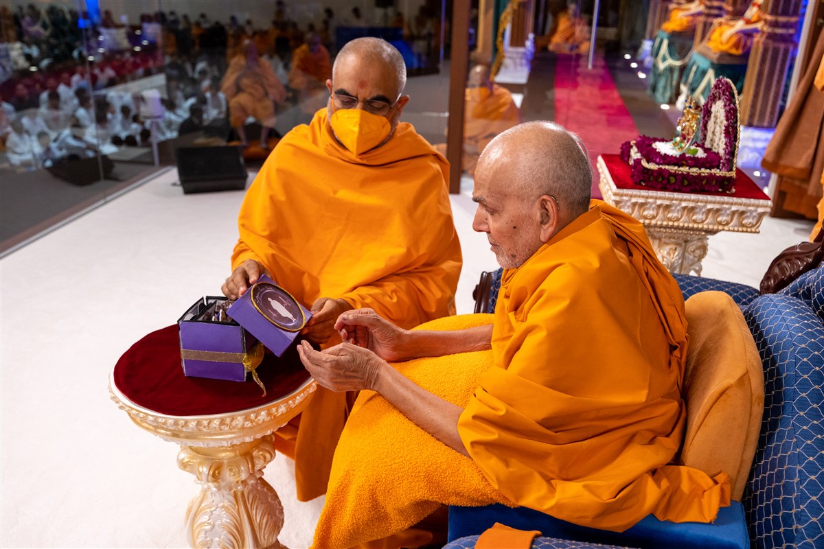 Yogvivekdas Swami offers Swamishri a decorative gift prepared by the mahilas