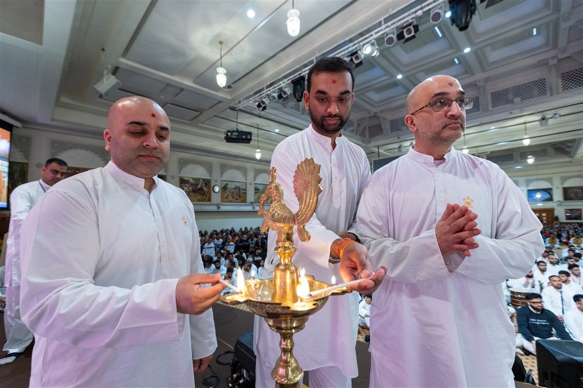Senior volunteers join Swamishri in lighting traditional lamps to ceremonially inaugurate Karyakar Din