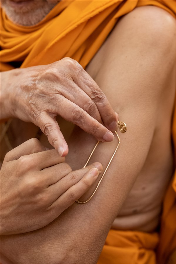 Swamishri applying a tilak on his arm