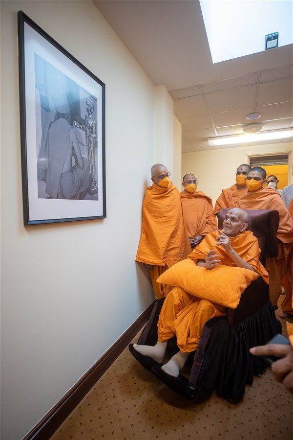 Swamishri observes a photograph in the sant ashram from the opening of the Mandir in 1995