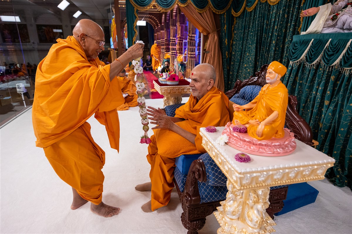 Tyagvallabhdas Swami honours Swamishri with a decorative lotus flower garland