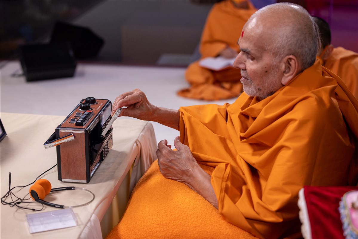 Swamishri inserts the tape into the cassette player as a part of the special evening programme