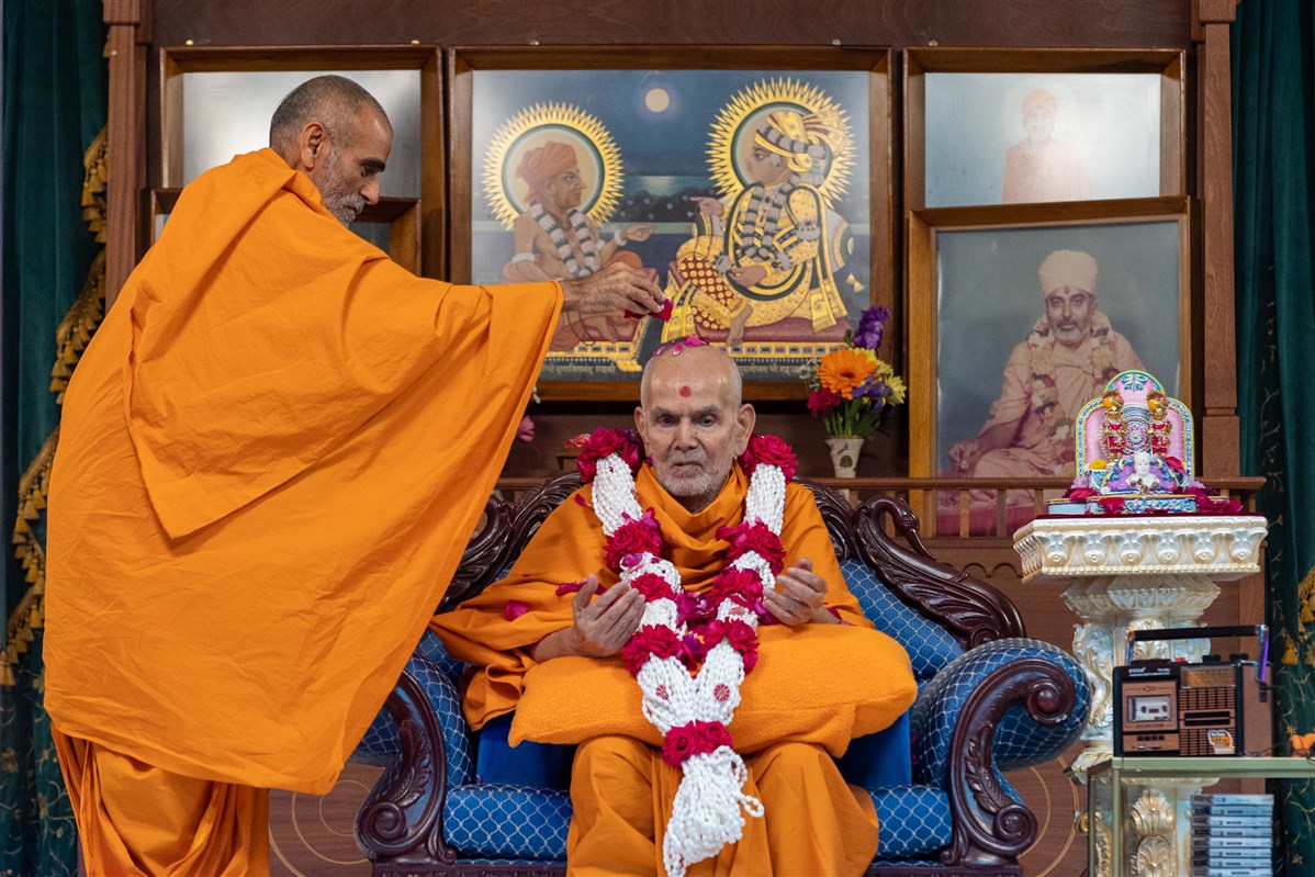 Anandswarupdas Swami honours Swamishri with rose petals