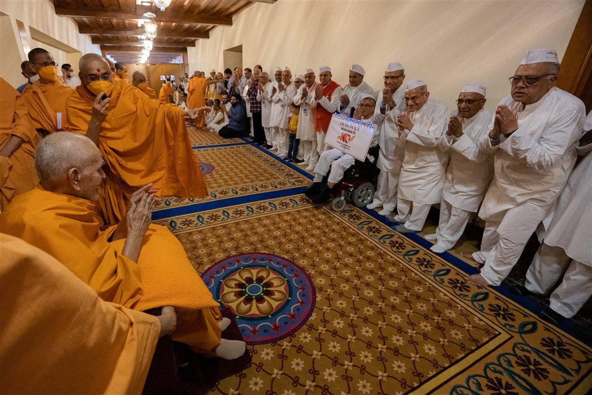 Swamishri greets senior devotees with folded hands