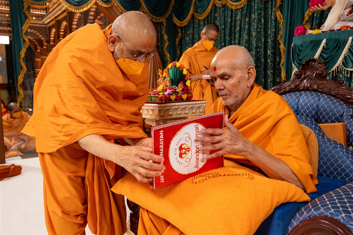 Aksharviharidas Swami offers a decorative card to Swamishri inviting him to bless Vadil Din