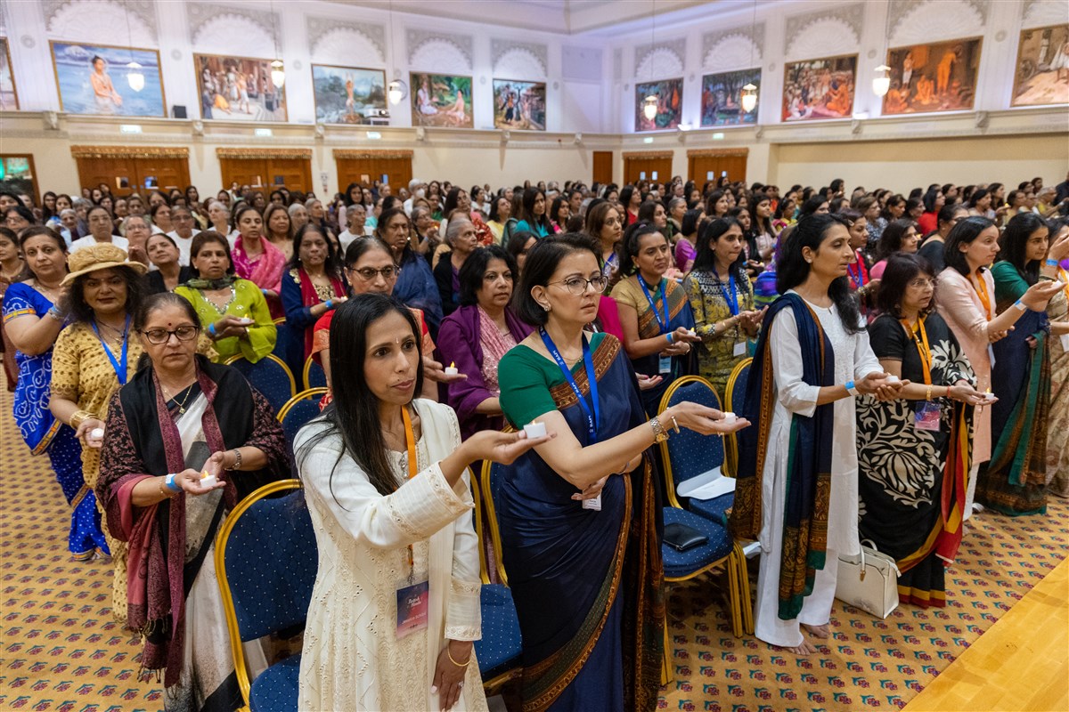 Guests join Swamishri in the evening arti