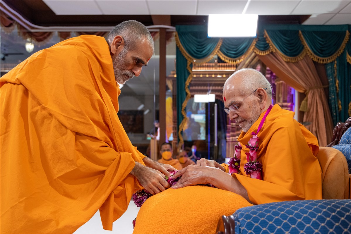 Anandswarupdas Swami honours Swamishri with a garland of fresh flowers