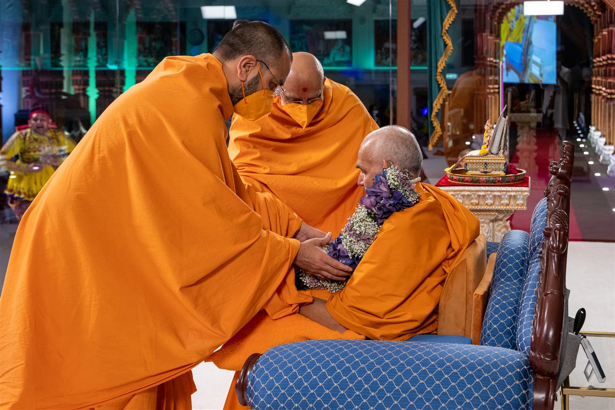 Tyagprakashdas Swami and Yogikirtandas Swami honour Swamishri with a decorative garland