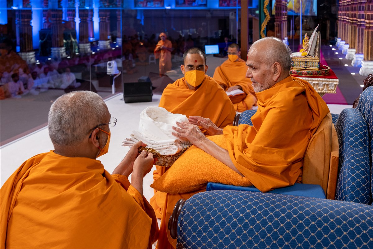 Prabuddhmunidas Swami and Paramtattvadas Swami present a pagh and gatariyu to Swamishri as a part of the programme