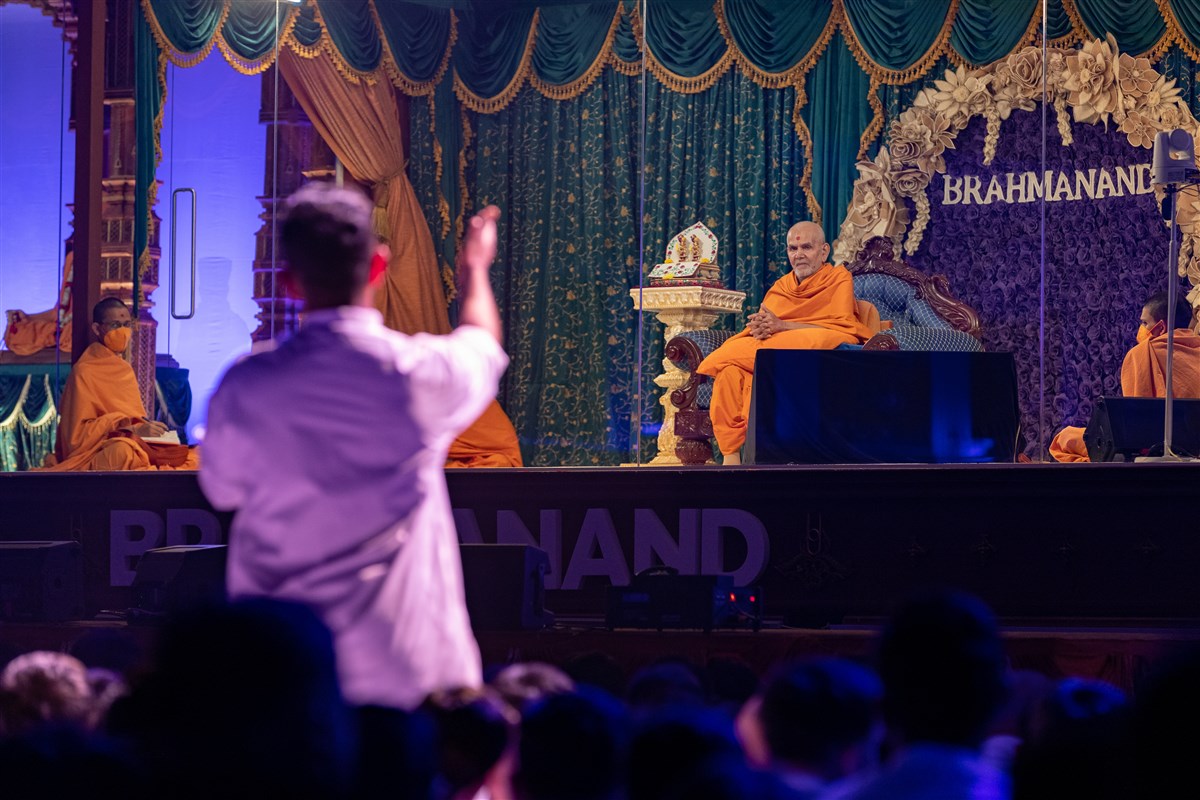 The youth interacts with Swamishri as he watches on
