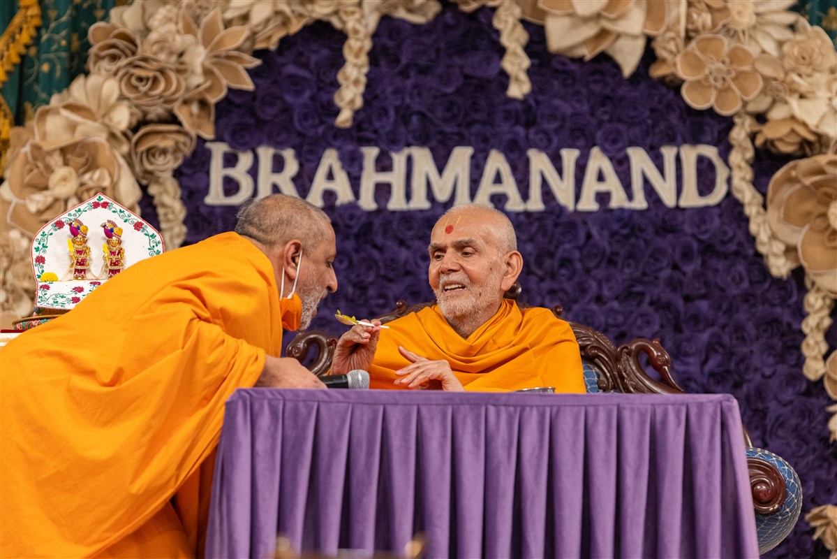 Swamishri offers a spoonful of 'parvar' to Anandpriyadas Swami as part of the interactive session