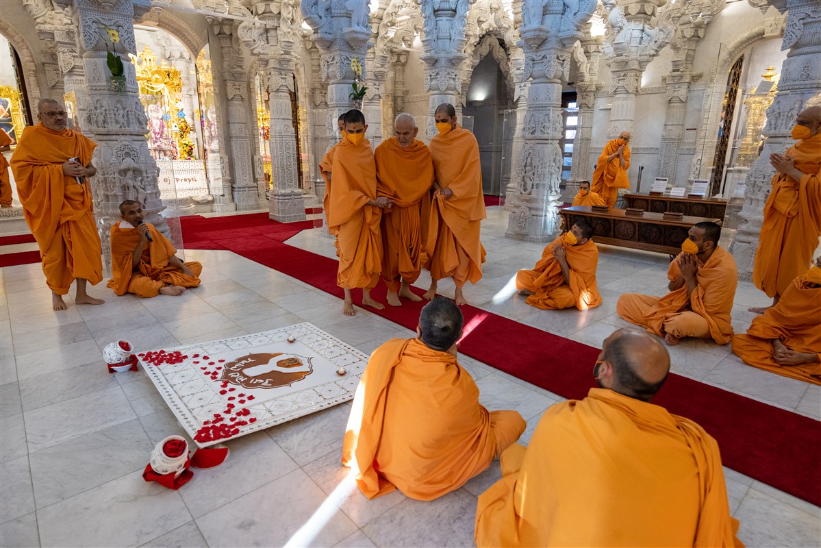 Swamishri observes a decorative piece of artwork on the theme of today’s Sanyukta Din, ‘Kevā Motā Bhāgya’, based on a letter written by Swamishri from Nenpur in 2020