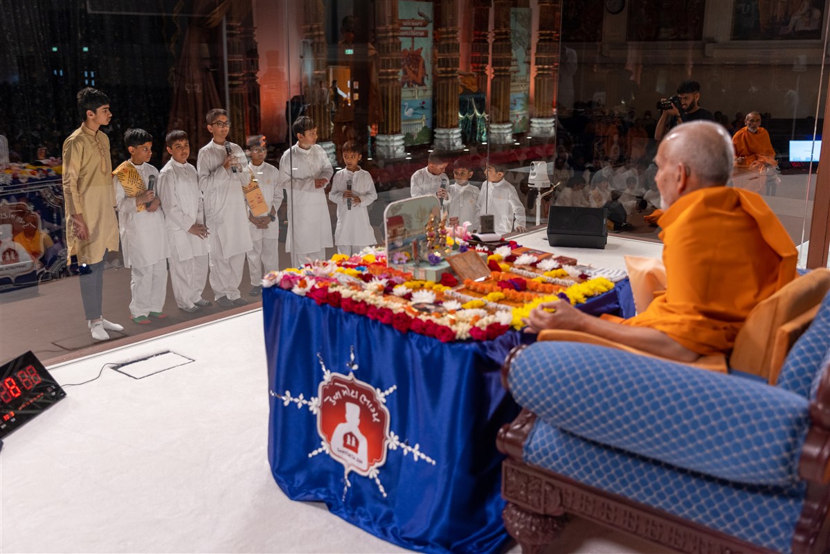 Children recite scriptural passages while Swamishri performs his puja