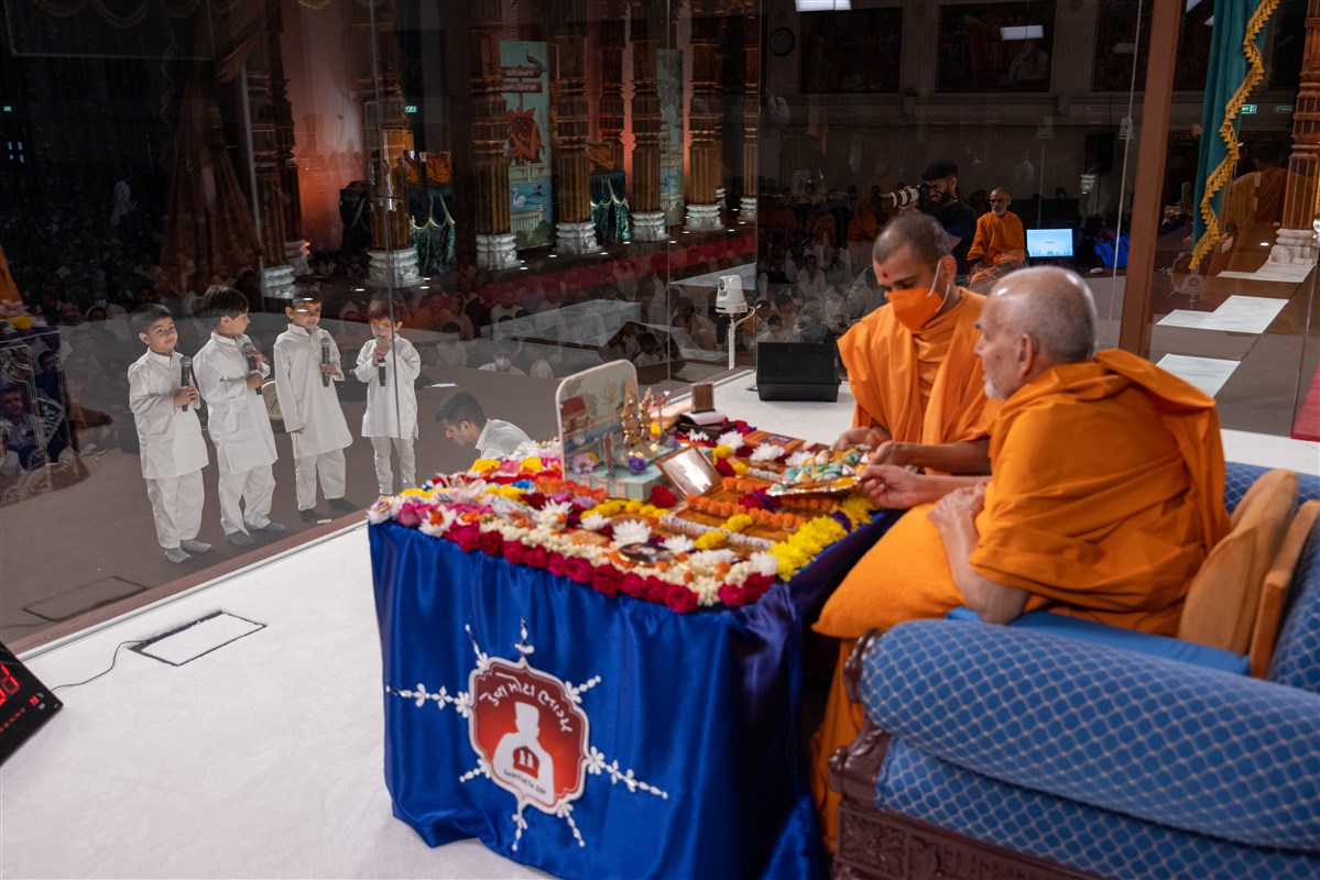 Children recite scriptural passages as Swamishri offers thal to the murtis