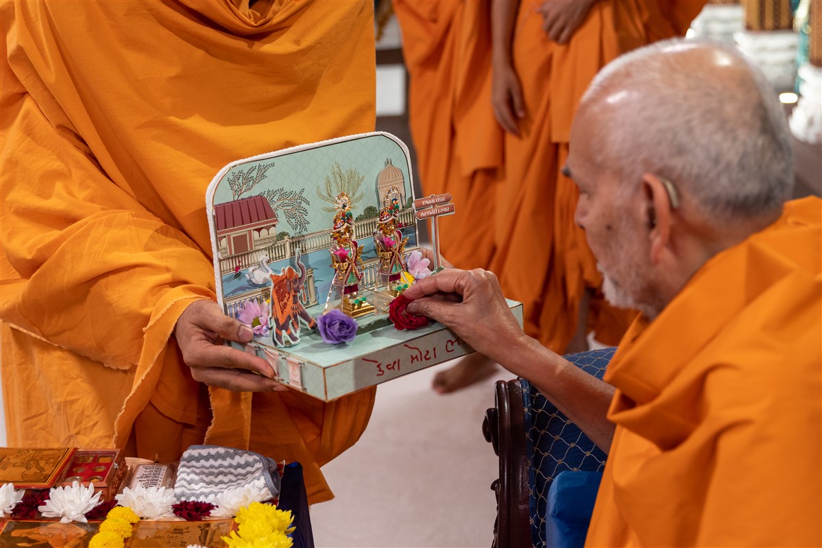 Swamishri offers a rose to Shri Harikrishna Maharaj and Shri Gunatitanand Swami Maharaj