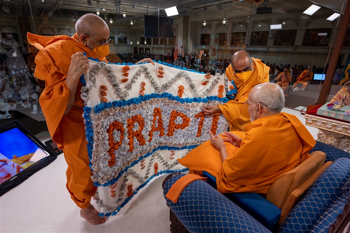 Aksharviharidas Swami and Satyavratdas Swami present a decorative shawl to Swamishri