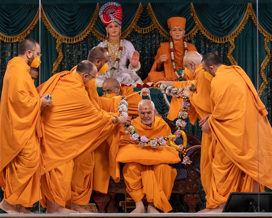 Swamis honour Swamishri with a decorative garland...