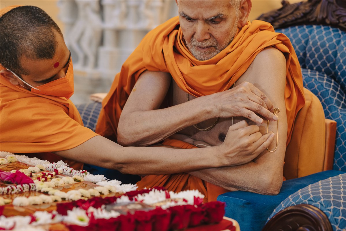 Swamishri applying a tilak on his left arm