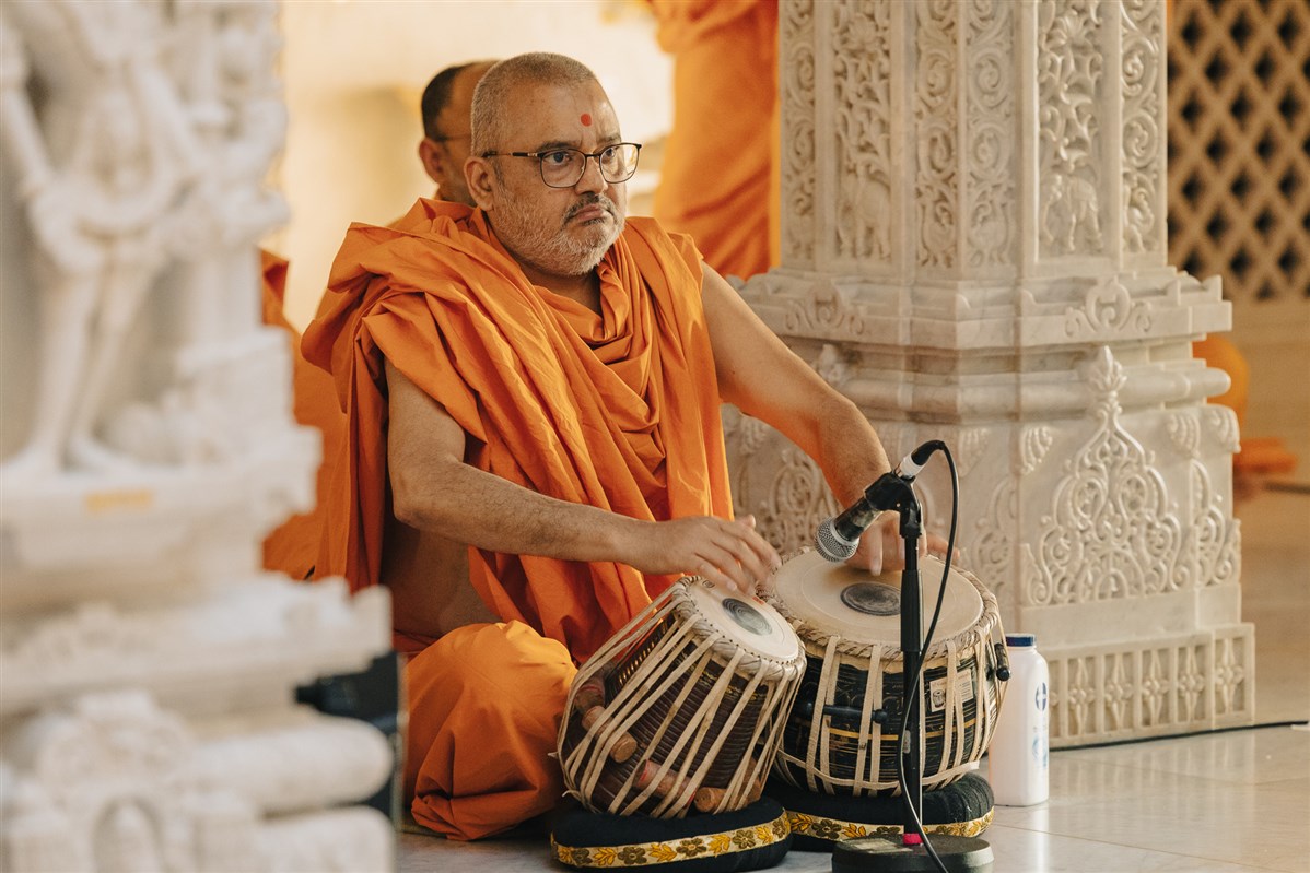 Bhadreshdas Swami accompanies the singing on the tabla during Swamishri's puja