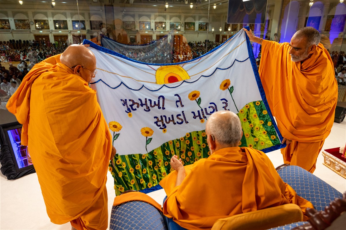 Sadguru Tyagvallabhdas Swami and Anandswarupdas Swami present a decorative shawl to Swamishri