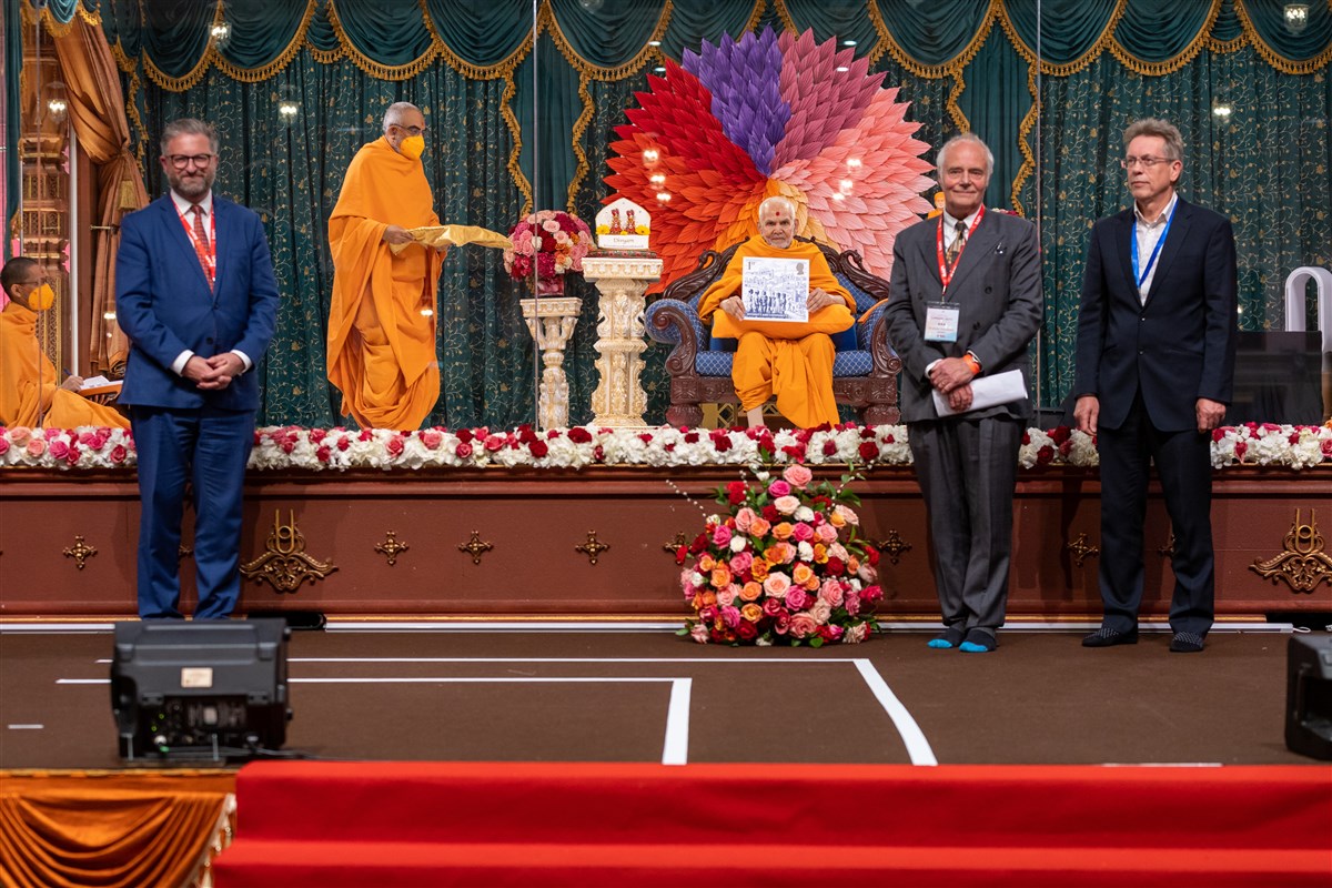 Swamishri presents the Coronation Stamp to the assembly, with David Gold (Director of External Affairs & Policy, Royal Mail), Andrew Davidson (artist) and Ian Chilvers (design consultant) 