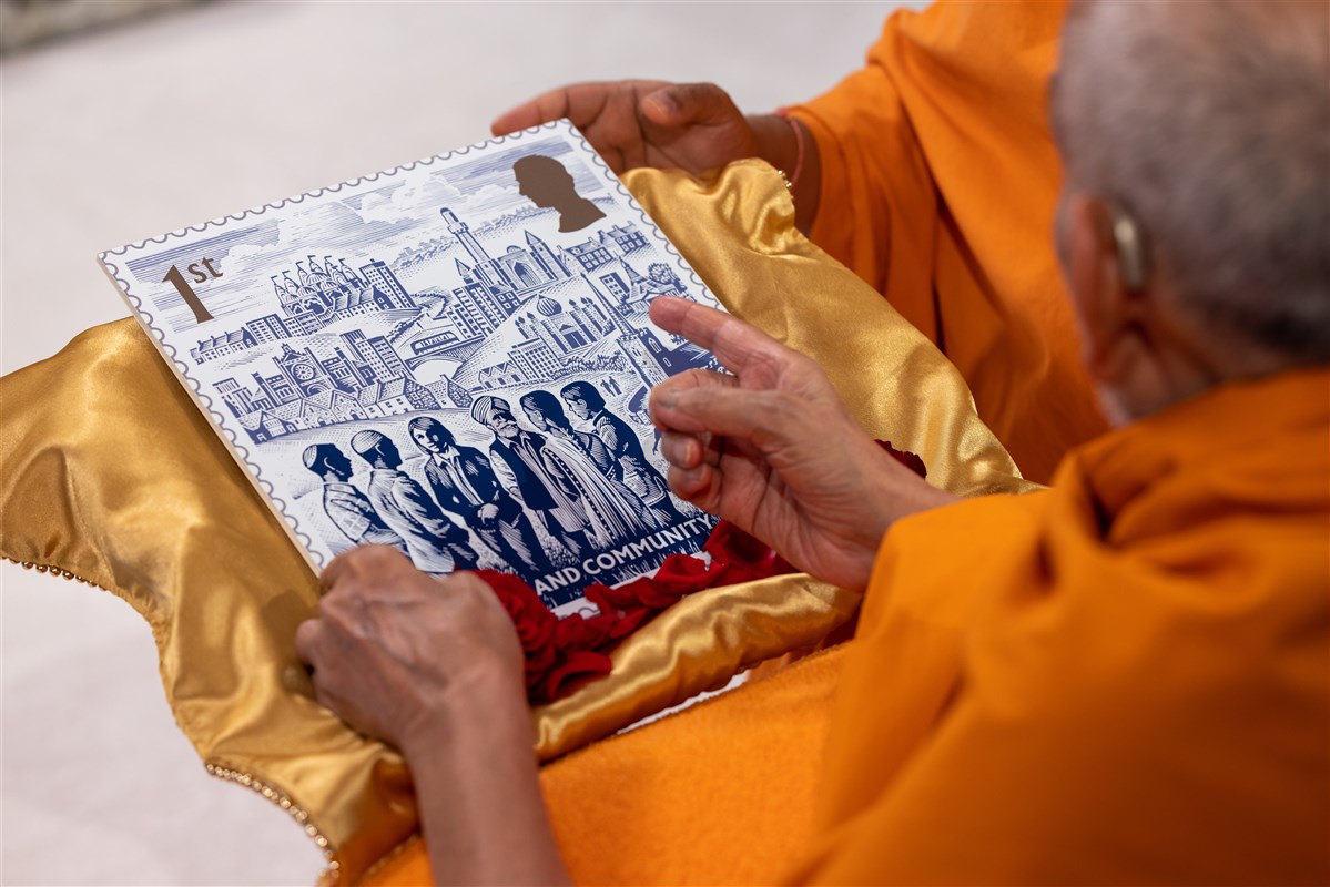 Swamishri observes a large replica of the coronation stamp, pointing out the Mandir upon the horizon