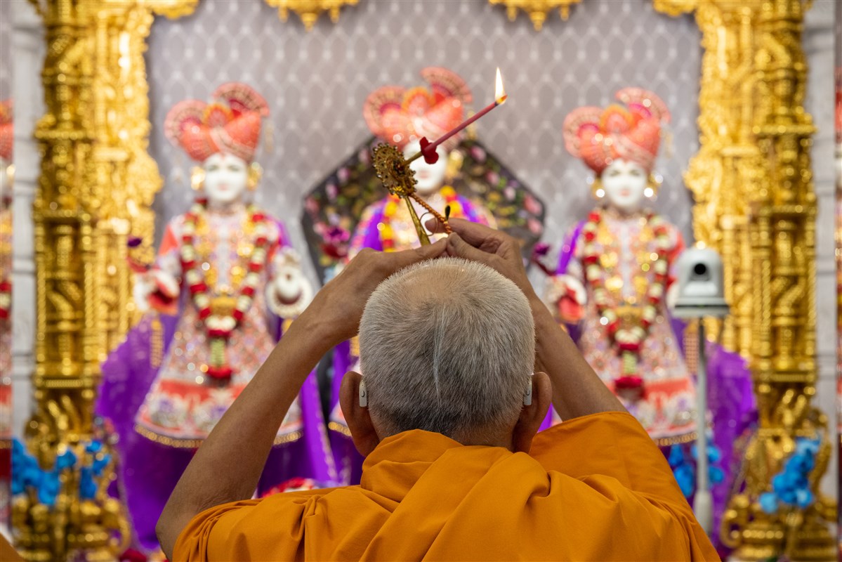 Swamishri performing the morning arti at the central shrine