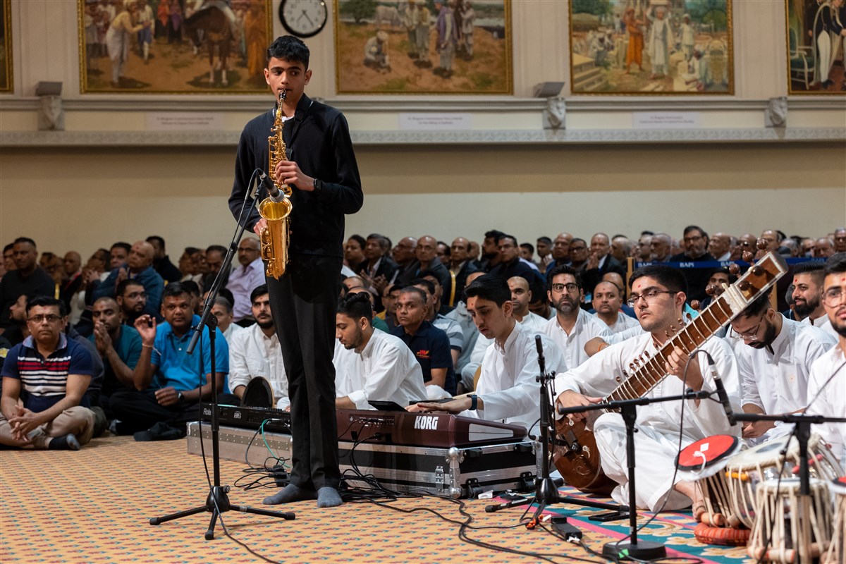 Young devotees perform the saxophone and sitar in Swamishri's puja