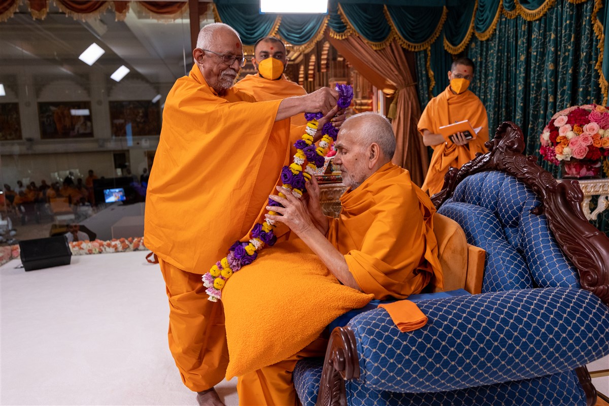 Sadguru Swayamprakashdas Swami (‘Doctor Swami’) honours Swamishri with a flower garland