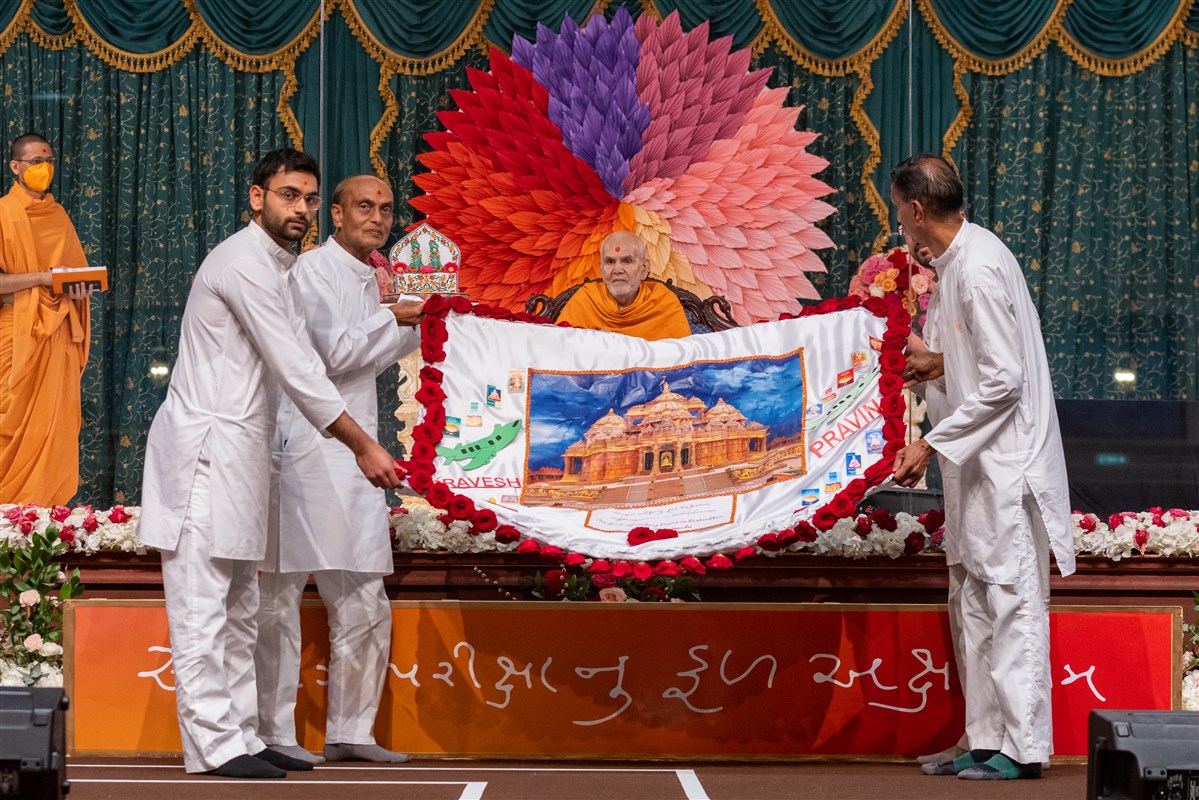 Volunteers offer Swamishri a decorative shawl