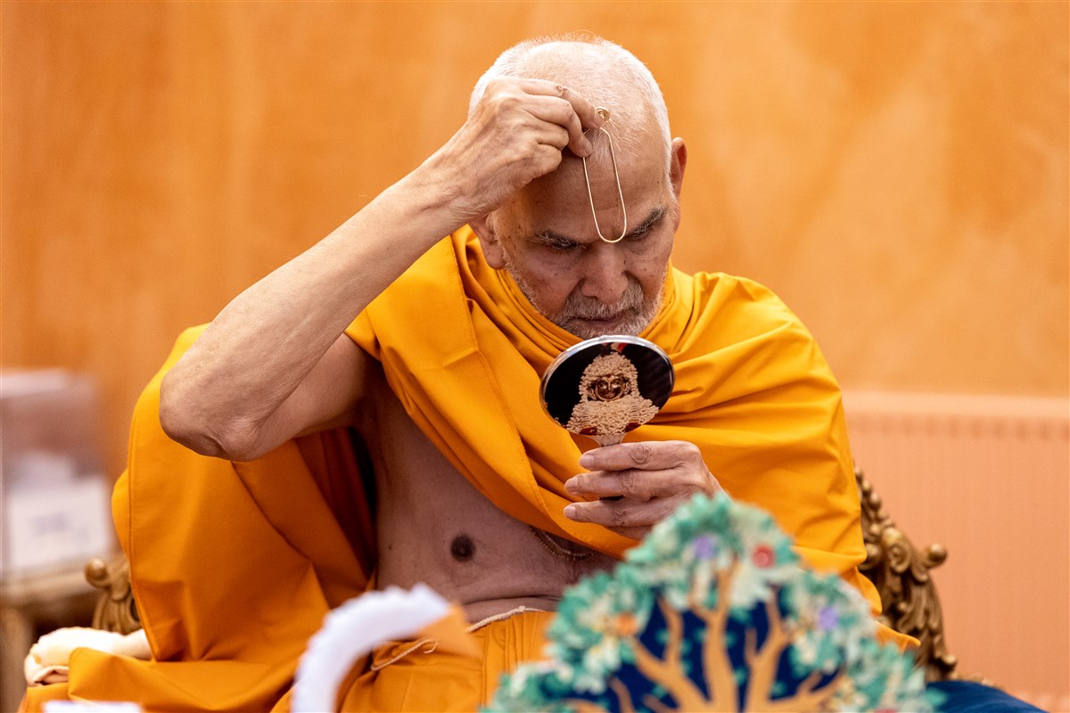 Swamishri applies a tilak to his forehead