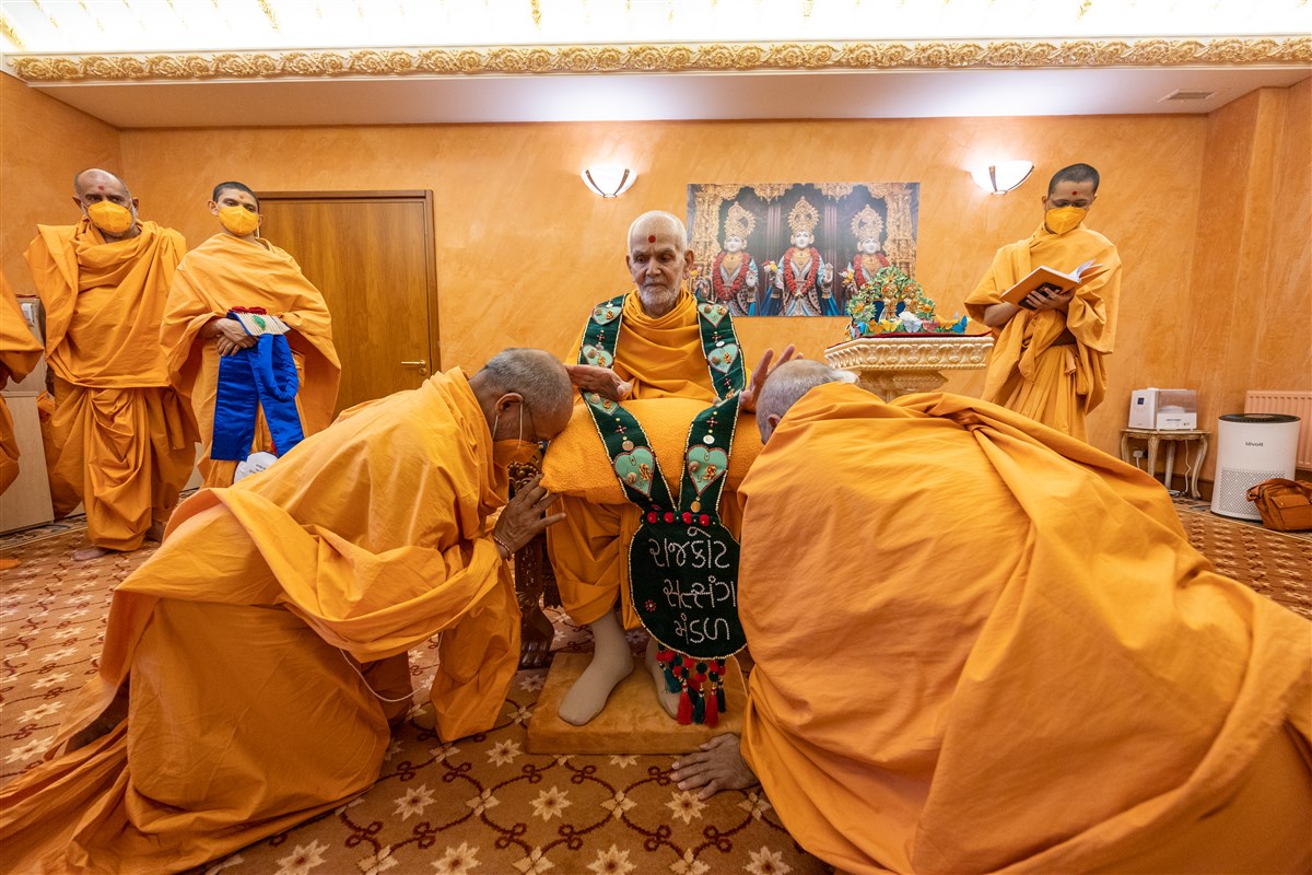 Aksharjivandas Swami and Krishnaswarupdas Swami honour Swamishri with a decorative garland