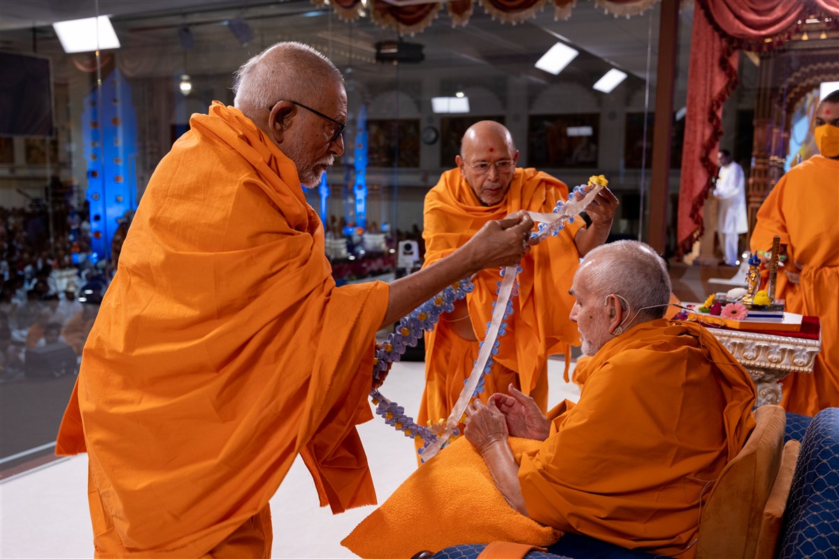 Sadguru Bhaktipriyadas Swami and Sadguru Tyagvallabhdas Swami honour Swamishri with a decorative garland