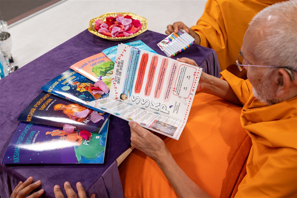 Swamishri looks through one of the children's books