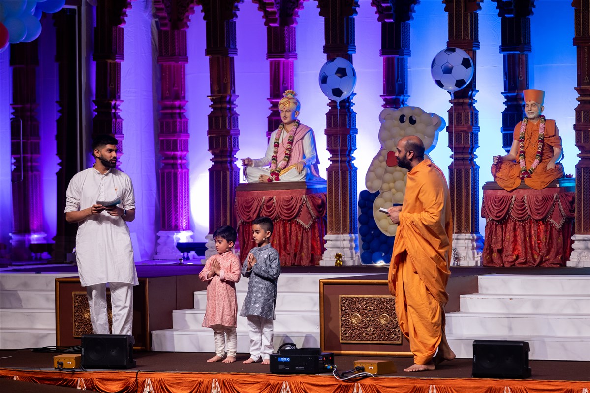 The evening assembly commences with an interactive programme between Akhandyogidas Swami, a volunteer and some shishus