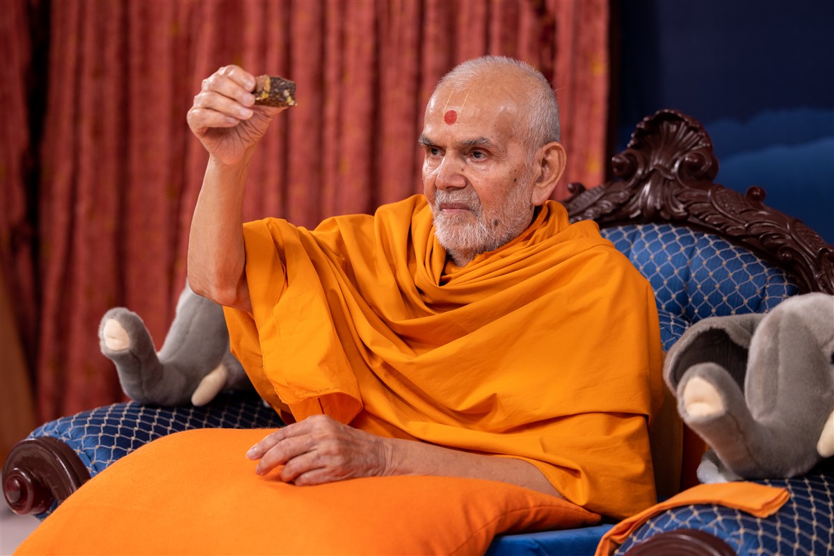 Swamishri offers a piece of chocolate crunch to all the children