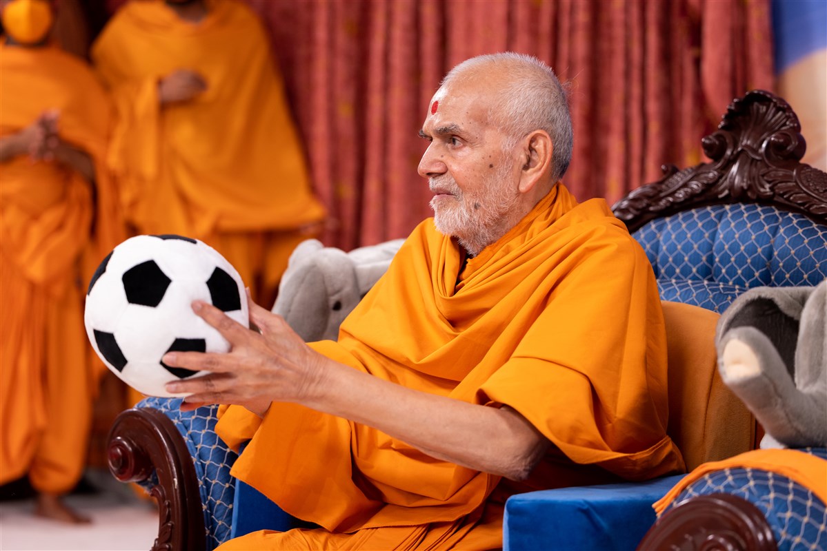 Swamishri plays with a football upon the children's request