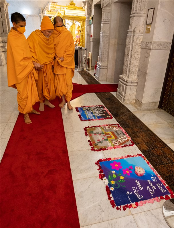 Swamishri observes decorative rangoli designs on his way to the darshan of Yogiji Maharaj and Pramukh Swami Maharaj